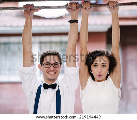 Man and woman hanging with hands on a bar. Classic clothes.