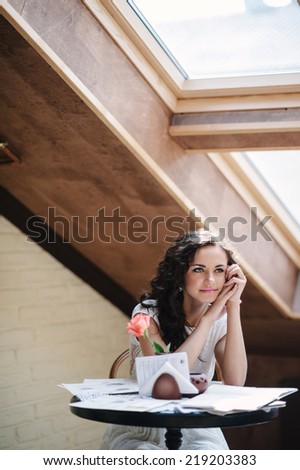 Girl in the soft light. Rose on the table.
