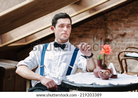 Man poses in cafe with rose on the table