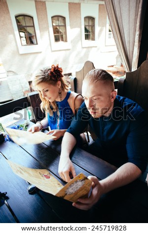 Man and woman looking at the menu in the restaurant. Outside restaurant view. Good-looking young people.