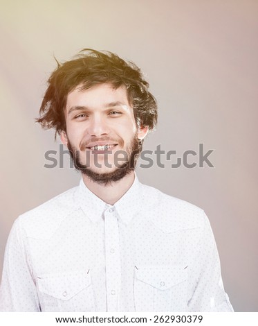 Cheerful young man with a messy hairdo. Light background.
