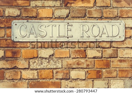 \'Castle Road\' sign on a weathered wall vintage look weathered wall closeup