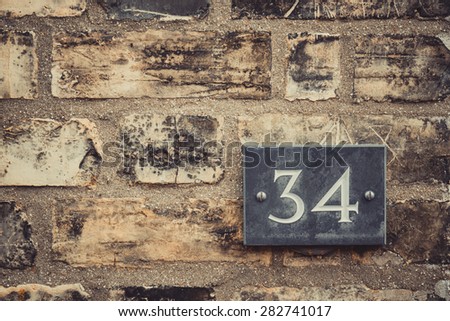House number 34 thirty four plate on brick wall texture closeup