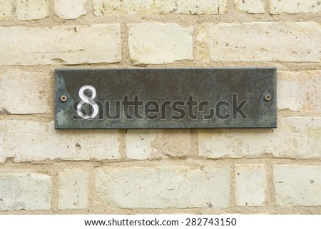 8 Eight engraved on stone plate mounted on brick wall closeup