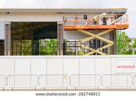 Builders on elevated hydraulic platform at a construction site, Cambridge, England
