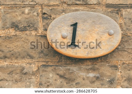 Wooden plate Number 1 one on a brick wall conceptual image closeup