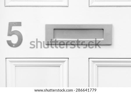 Door number 5 five and letterbox monochrome conceptual image closeup