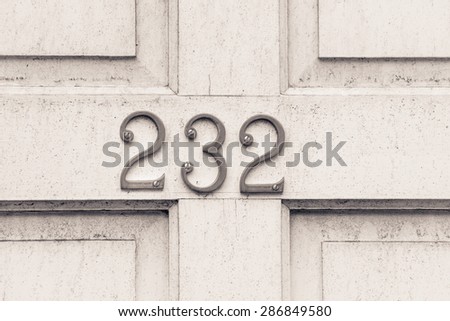 Door number 232 two hundred thirty two  conceptual monochrome image closeup