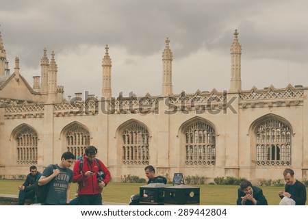 CAMBRIDGE, ENGLAND - 7 MAY 2015: Students sitting outside Colleges of Cambridge University, England