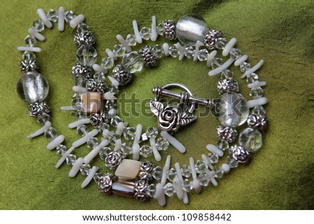 Stone and silver necklace arranged on a background of silk