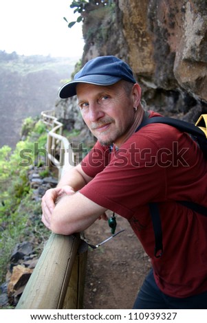 Head and shoulders of male hiker looking sideways into the camera with a baseball hat on