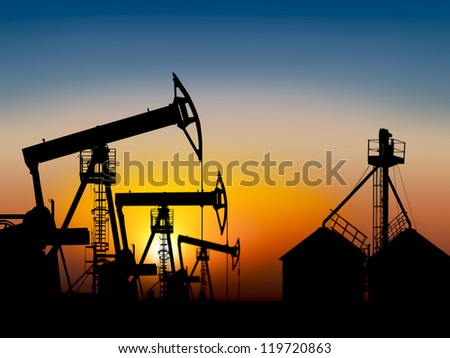 extracting petroleum in a oil field at sunset near the storage tank