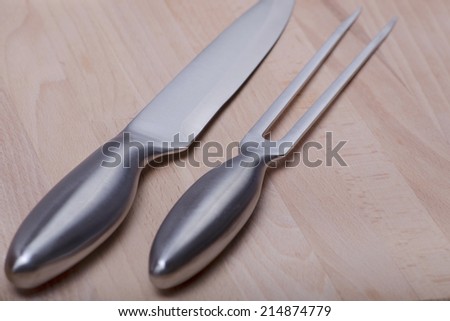 metallic sharp kitchen instruments on cutting board made of wood