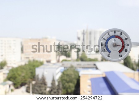 Thermometer outside the window shows the heat of a summer day in the city