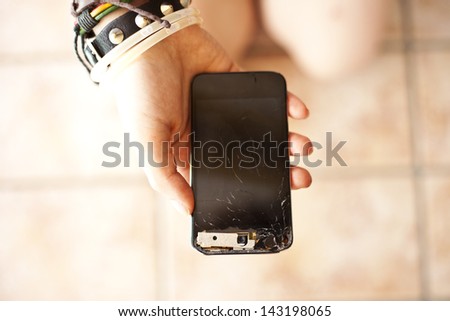 A teenage girl holding a broken smartphone