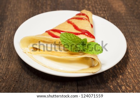 pancake with cream cheese and strawberry jam on a wooden texture