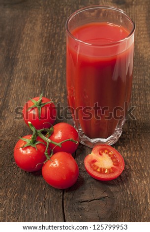 glass of tomato juice with tomatoes on a wood texture
