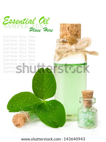 bottle of scented oil and leaf clover in drops of water isolated on white