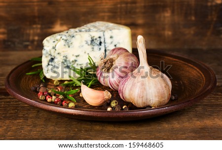 blue cheese , garlic , grapes and spices on wooden background