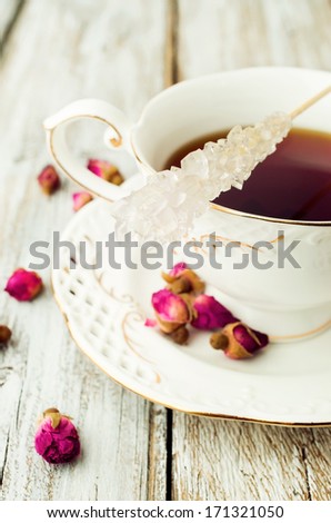 graceful white cup and saucer with tea,  dry roses and sugar on a stick