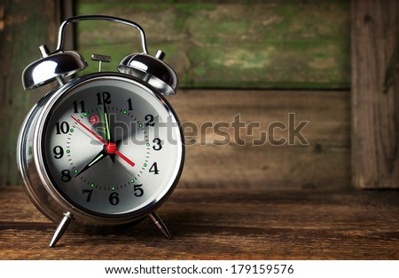 Silver retro alarm clock on wooden background