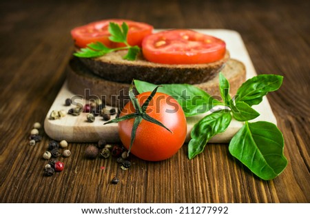 rustic food : sandwiches of rye bread with tomato and basil on a wooden background