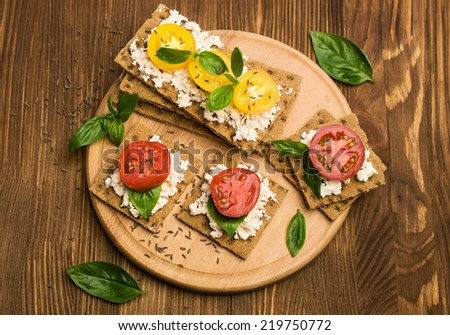 rye bread with cheese, tomatoes, basil and thyme on wooden