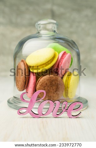multicolored macaroons in a glass bell jar on table