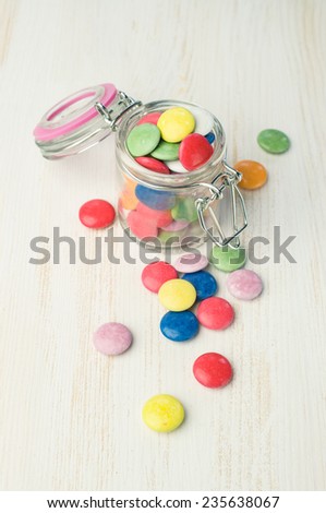 Colorful candies in a glass jar on table