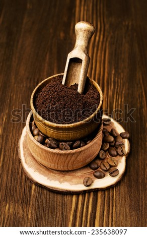 Ground coffee in a wooden bowl with a shovel on a wooden