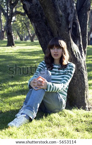 Girl sitting under tree at autumn