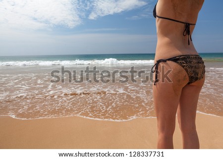 Perfect young women back on beach with black swimsuit and covered with sand
