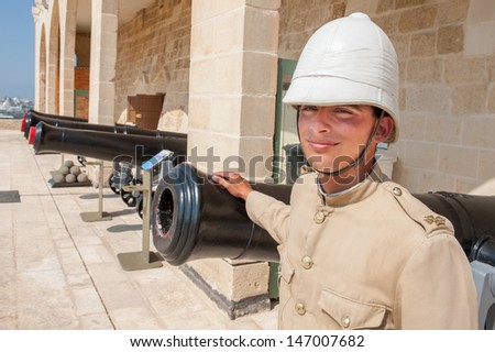 VALLETTA, MALTA - JULY 20: Unidentified man dressed in old English military uniform, standing in front of cannons on July 20, 2013. Despite independence Maltese people still remember the English era