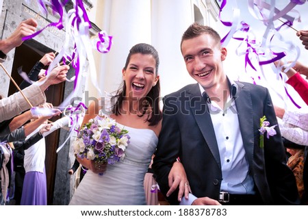 Newlyweds coming out of church after wedding, surrounded with twirling wedding favor ribbon sticks