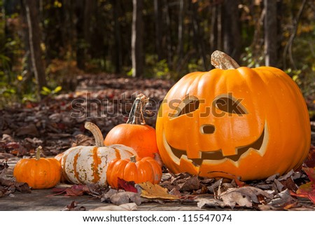 Jack O Lantern and pumpkins on a wood bridge covered with leaves