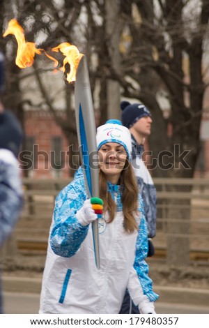 TVER, RUSSIA - MAR 2, 2014: Girl torchbearer runs with torch in hand on the Paralympic Torch Relay. Unlike traditional Olympic organizers themselves determine location and method of lighting the torch