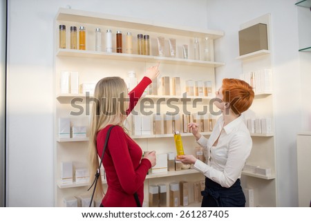 Young woman comparing cosmetics with saleswoman in a cosmetics shop