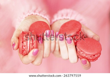 Women\'s hands with a beautiful pink manicure holding macaroons