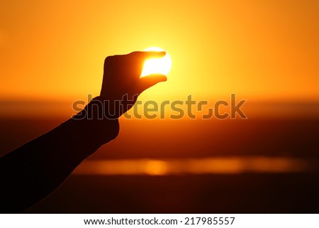 Silhouette of hand and fingers at sunset with ocean background