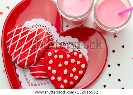 Plate of red heart cookies and glasses of strawberry milk ready for Valentines Day