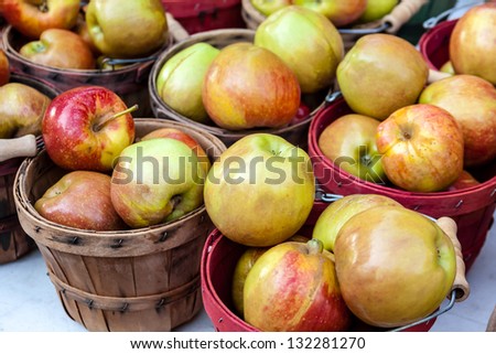 Display of fresh locally grown red pears in colorful bushel baskets on display at local farmers market