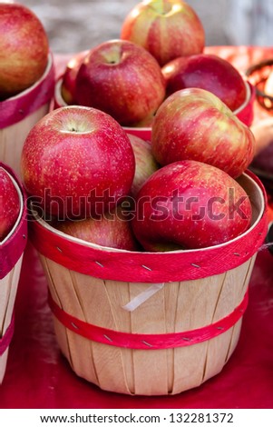 Fresh organic red apples in brown bushel basket on display at local farmers market