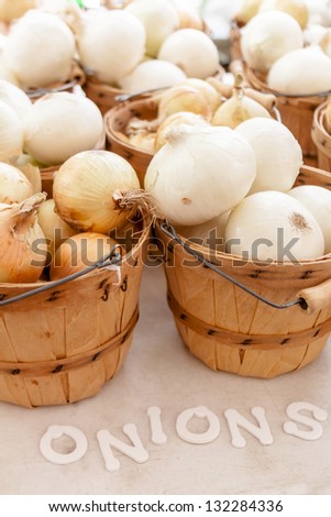 Home grown organic white onions in brown bushel basket on display at local farmers market