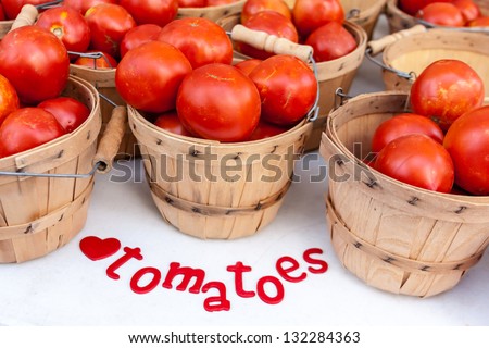 Fresh organic red tomatoes in brown bushel baskets on display at farmers market