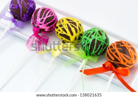 Row of brightly colored cake pops sitting on white plate