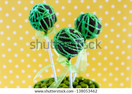 Chocolate cake pops with green swirl glitter sugar decorations against yellow polka dot background