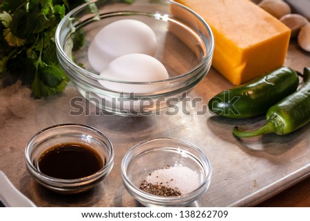 Eggs, jalapenos, kosher salt, cheddar cheese cilantro and soy sauce ingredients sitting on a silver pan