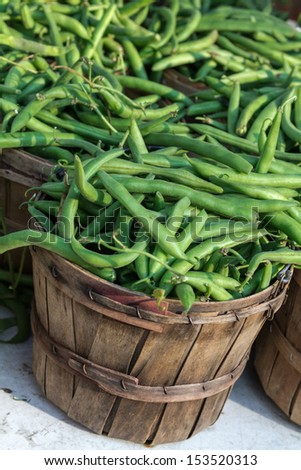 Fresh locally grown green beans in brown bushel baskets on display at local farmers market
