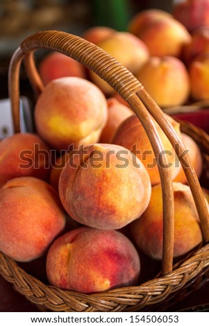 Large ripe yellow peaches in wicker basket for sale in country store