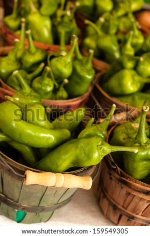 Organically grown jalapeno peppers in small brown baskets for sale at local farmers market